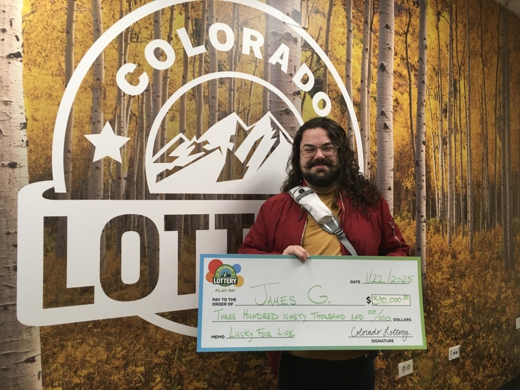 James G. holding a check for $390,000 in front of Colorado Lottery background.