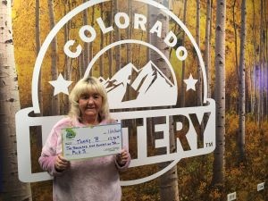 Tammy B. sosteniendo un cheque de gran tamaño por $2,900 frente al fondo de la Lotería de Colorado