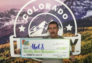 Abel S. holding an oversized check for $23,000 in front of Colorado Lottery background