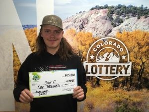 Cody C. holding an oversized check for $1,000 in front of Colorado Lottery backgroun