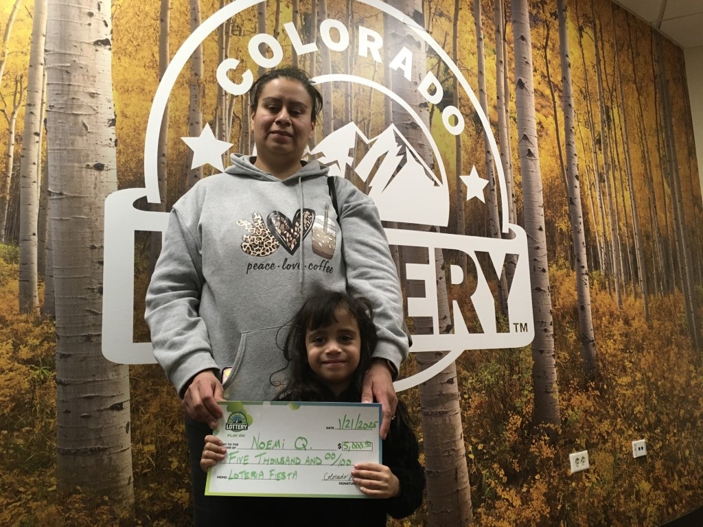 Noemi Q. sosteniendo un cheque por $5,000 frente a un fondo de la Lotería de Colorado.