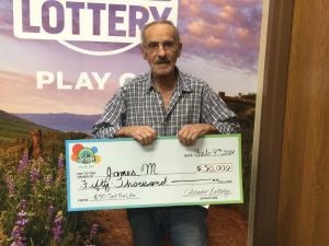 James M. holding an oversized check for $50,000 in front of Colorado Lottery background