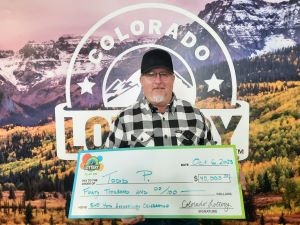 Todd P. holding an oversized check for $40,000 in front of Colorado Lottery background