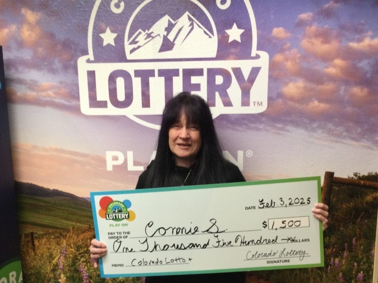 Connie S. sosteniendo un cheque gigante frente al fondo de la Lotería de Colorado