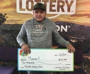 Manuel C. holding an oversized check for $10,000 in front of Colorado Lottery background