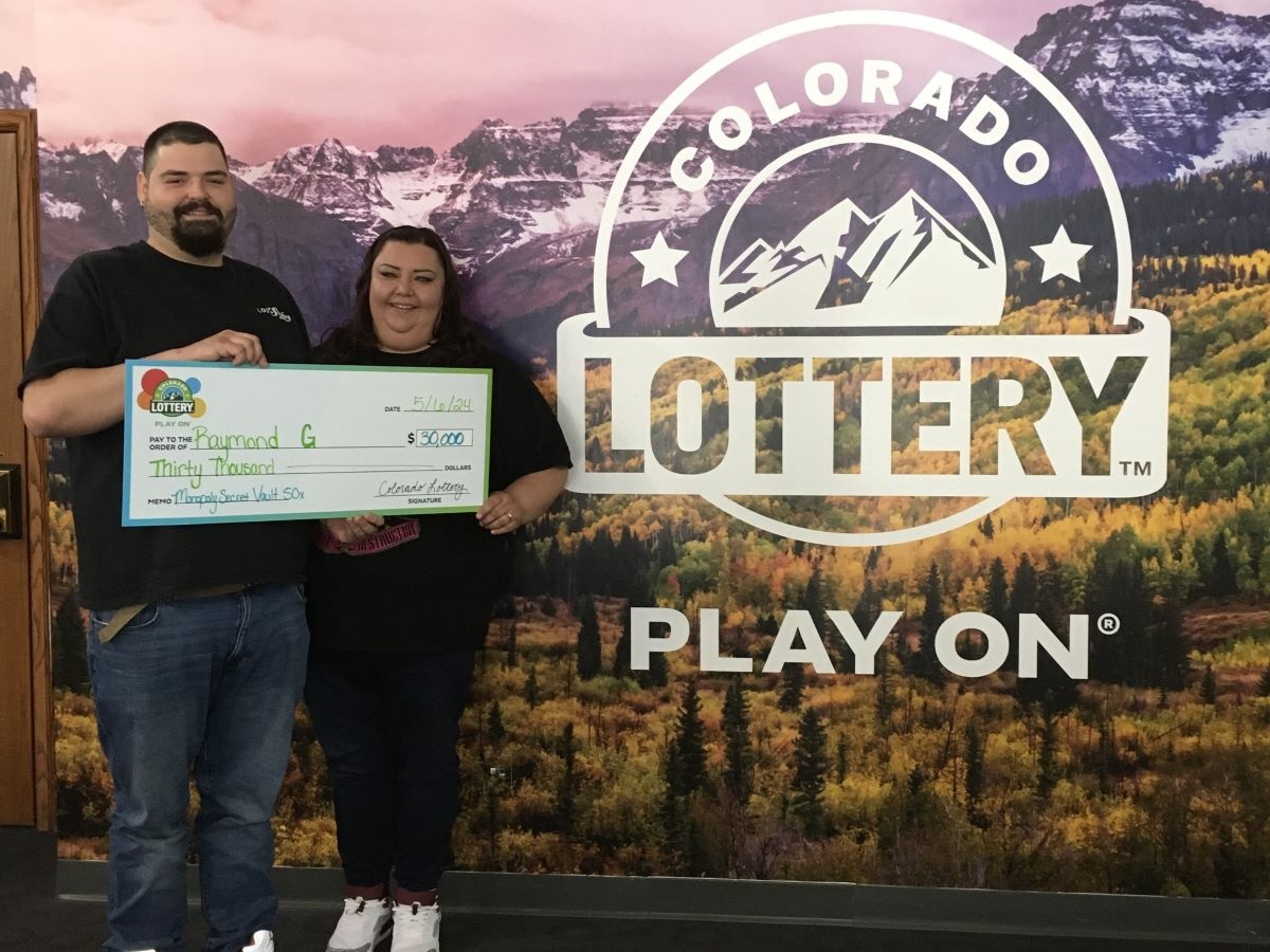 Raymond G. holding an oversized check for $30,000 in front of Colorado Lottery background