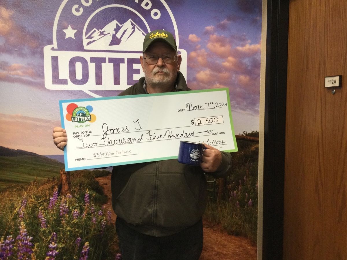 James T. holding an oversized check for $2,500 in front of Colorado Lottery background
