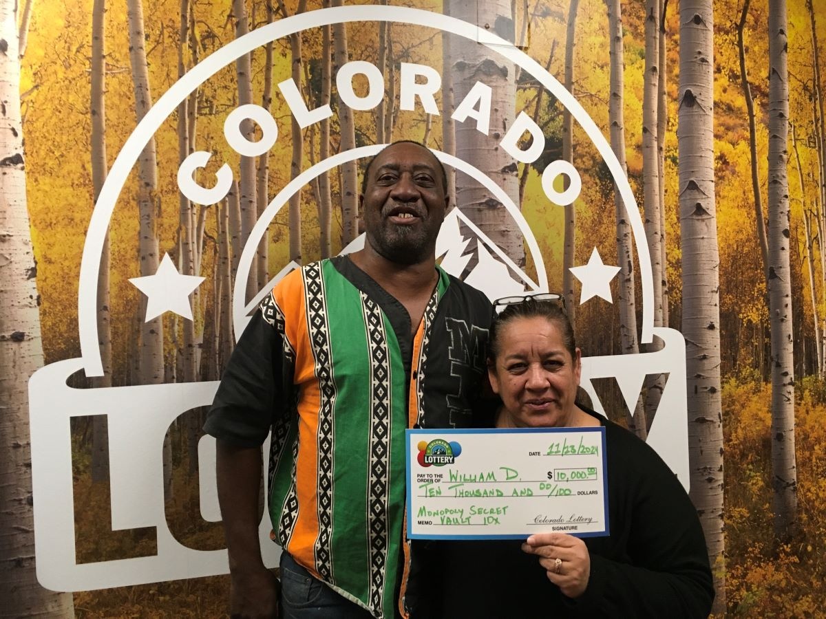 William D. holding an oversized check for $10,000 in front of Colorado Lottery background