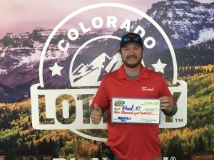 Paul P. holding an oversized check for $2,500 in front of Colorado Lottery background
