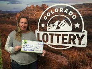 Keri K. sosteniendo el cheque de $1,000 frente al fondo de Colorado Lottery