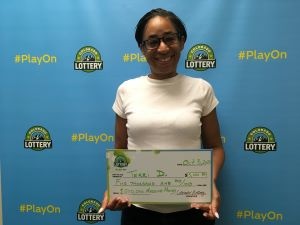 Terri D. of Aurora holding an oversized check for $5,000 in front of Colorado Lottery background