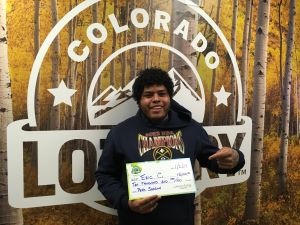 Eric C. holding an oversized check for $10,000 in front of Colorado Lottery background