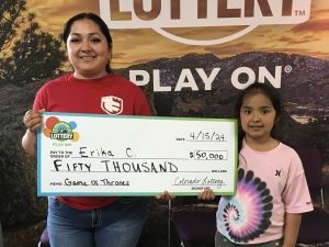 Erika C. holding an oversized check for $50,000 in front of Colorado Lottery background