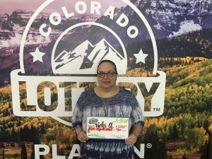 Vicki A. holding an oversized check for $5,000 in front of Colorado Lottery background