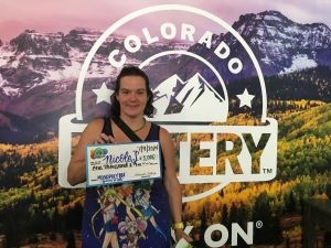 Nicole S. holding an oversized check for $1,000 in front of Colorado Lottery background