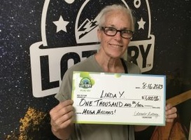 inda Y. of Denver holding an oversized check for $1,000 in front of Colorado Lottery background.