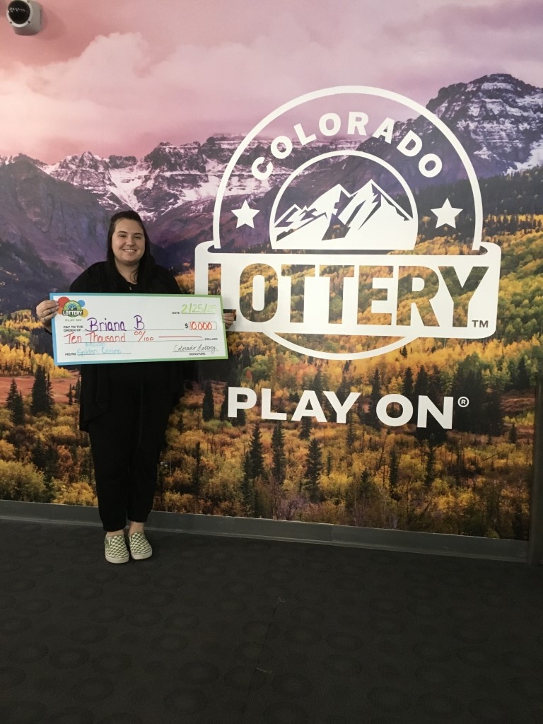 Winner holding oversized check in Colorado Lottery offices