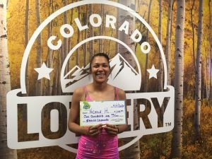 Nichole H. sosteniendo el cheque gigante de $1,000 frente al fondo de Colorado Lottery