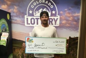 James D. holding an oversized check for $5,000 in front of Colorado Lottery background
