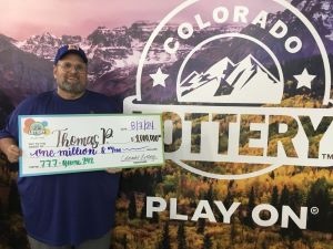 Thomas P. sosteniendo un cheque de gran tamaño por $1,000,000 frente al fondo de la Lotería de Colorado