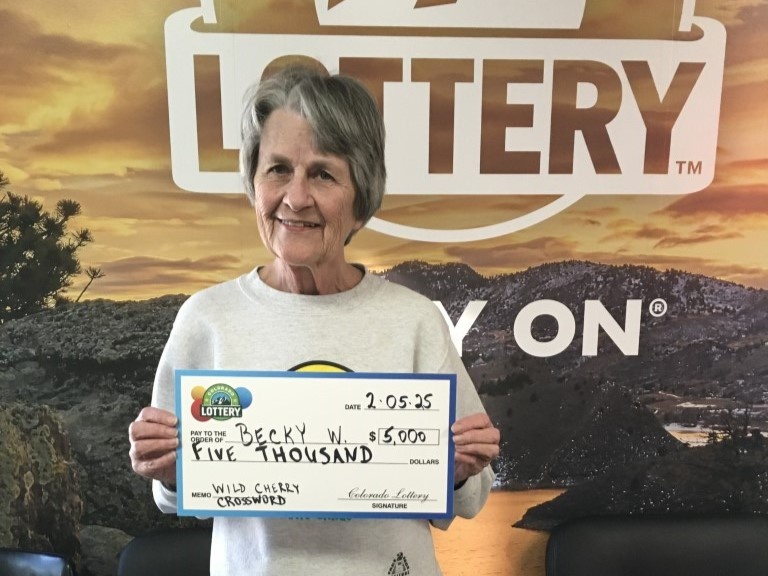 Becky W. holding an oversized check in front of Colorado Lottery background