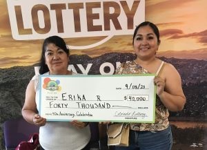Erika R. de Kersey sosteniendo un cheque de gran tamaño por $40,000 frente al fondo de la Lotería de Colorado.
