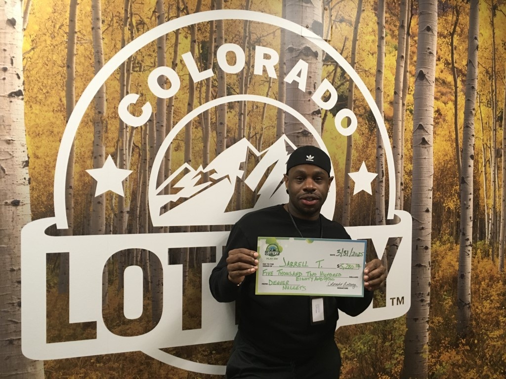 Ganador sosteniendo un cheque gigante frente al fondo de Colorado Lottery