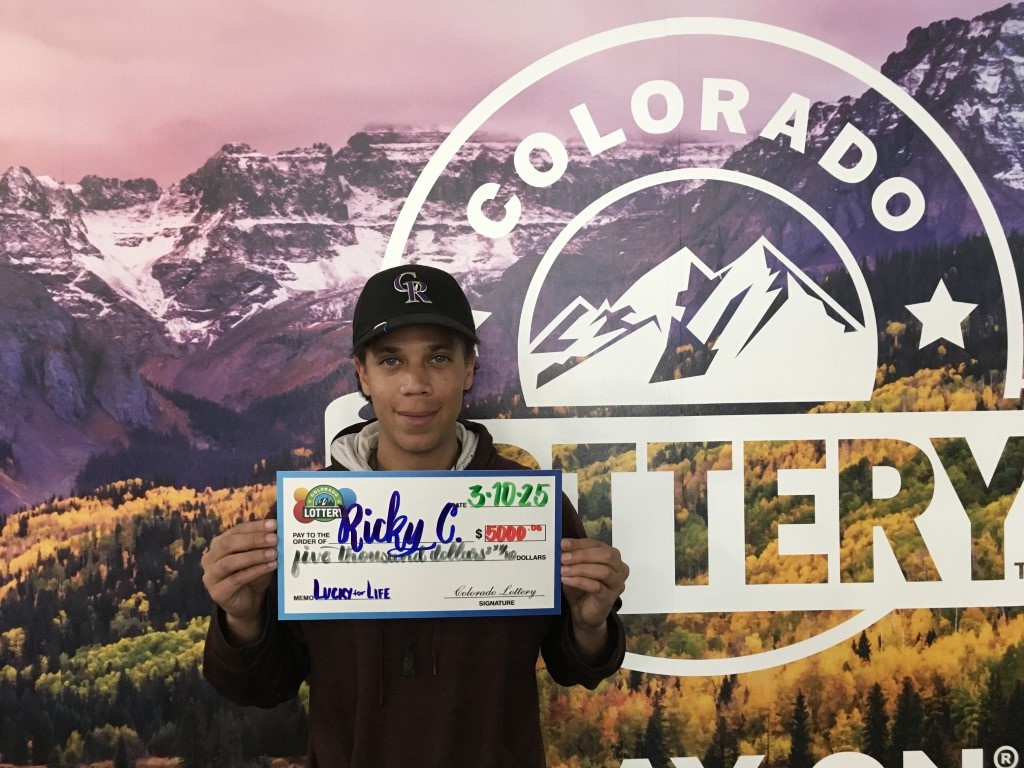 Winner holding oversized check in Colorado Lottery offices