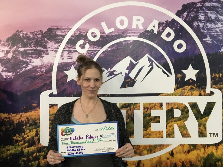 Natalia R. sosteniendo el cheque gigante de $20,000 frente al fondo de Colorado Lottery