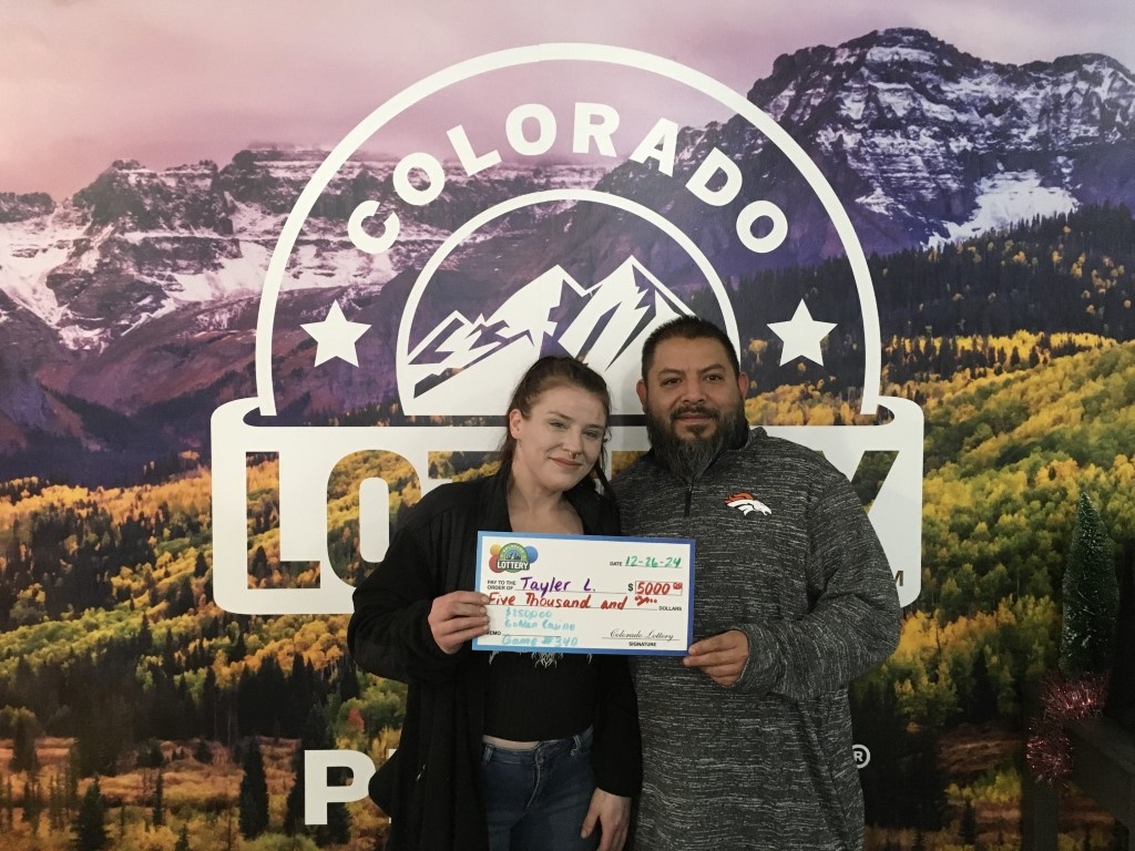 Tayler L. holding oversized check for $5,000 in front of Colorado Lottery background