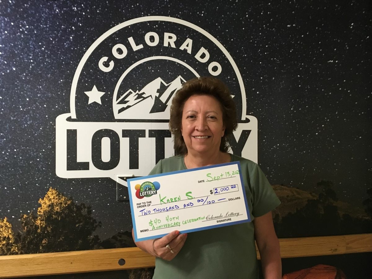 Karen S. of Aurora holding an oversized check for $2,000 in front of Colorado Lottery background.