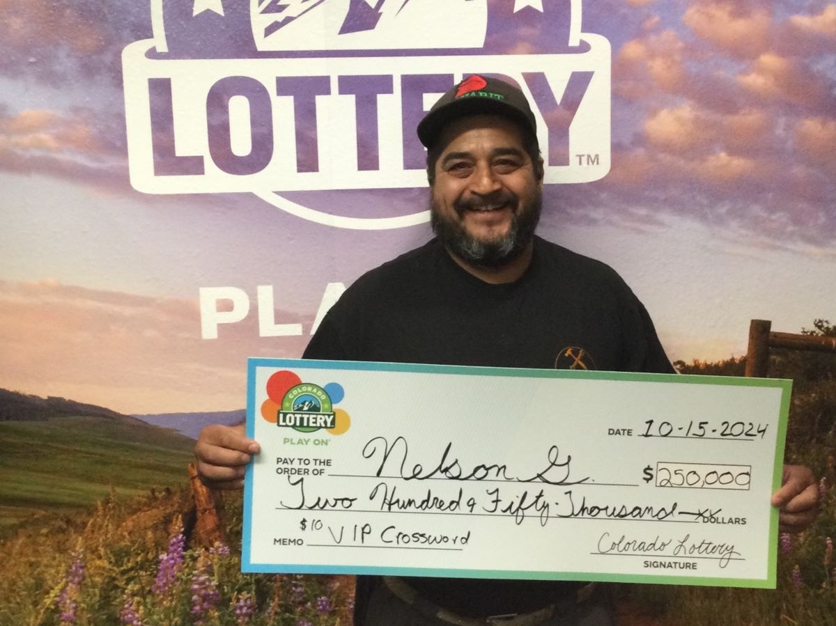 Nelson G. holding oversized check for $250,000 in front of Colorado Lottery background
