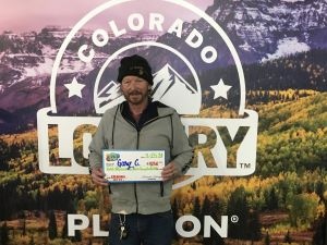 Gary C. sosteniendo el cheque gigante de $1,250 frente al fondo de Colorado Lottery
