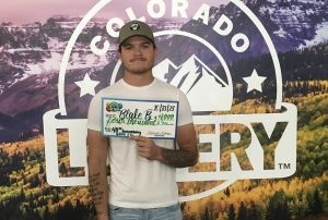 Blake B. holding an oversized check for $4,000 in front of Colorado Lottery background