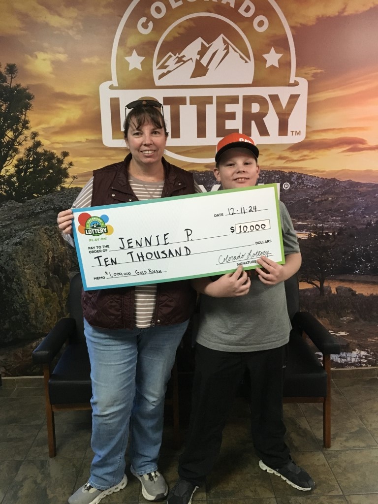 Jennie P. sosteniendo el cheque gigante de $10,000 frente al fondo de Colorado Lottery