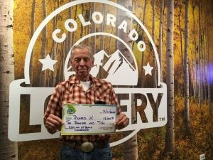 Richard W. sosteniendo un cheque gigante de $2,000 frente al fondo de la Lotería de Colorado