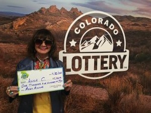 Alicia C. sosteniendo el cheque gigante de $1,500 frente al fondo de Colorado Lottery