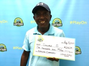Solomon S. de Denver sosteniendo un cheque de gran tamaño por $1,000 frente al fondo de la Lotería de Colorado.