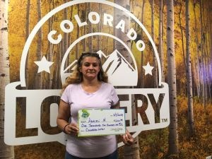 Araceli M. holding an oversized check for $1,200 in front of Colorado Lottery background