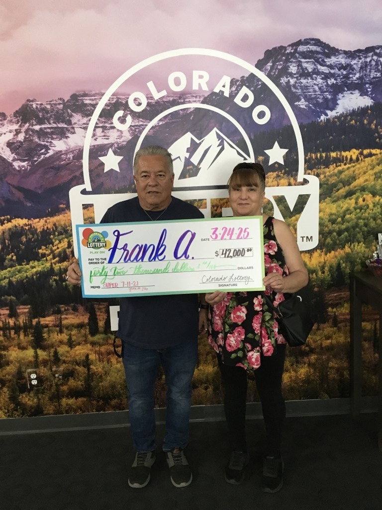 Winner holding oversized check in Colorado Lottery offices
