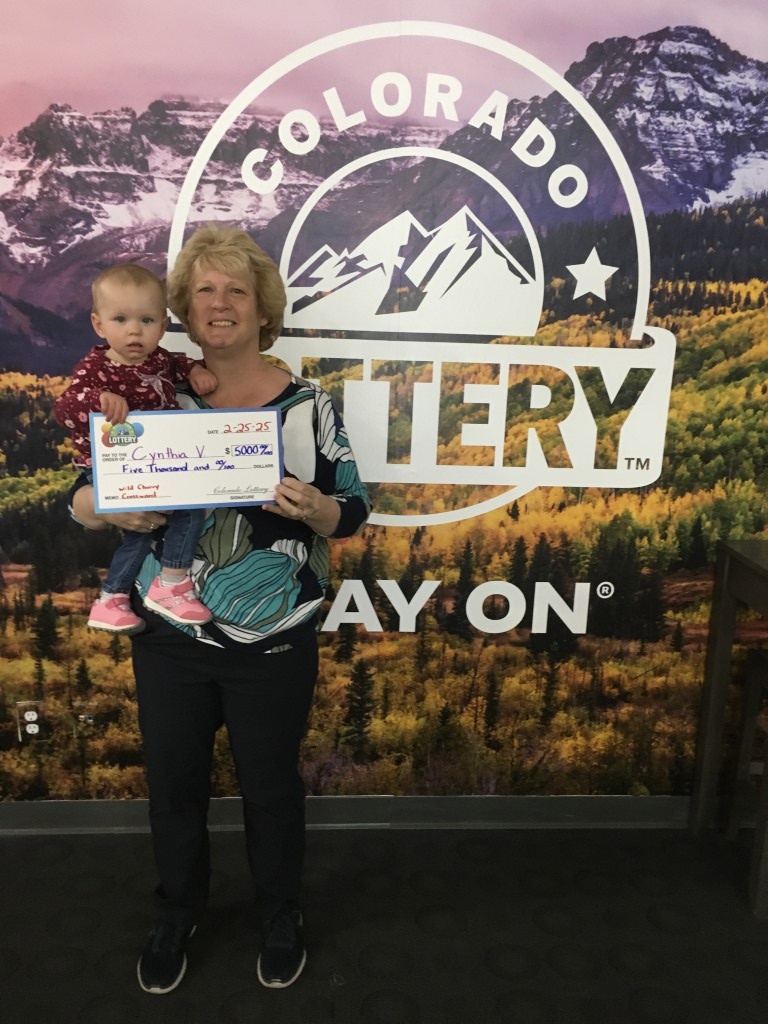 Winner holding oversized check in Colorado Lottery offices