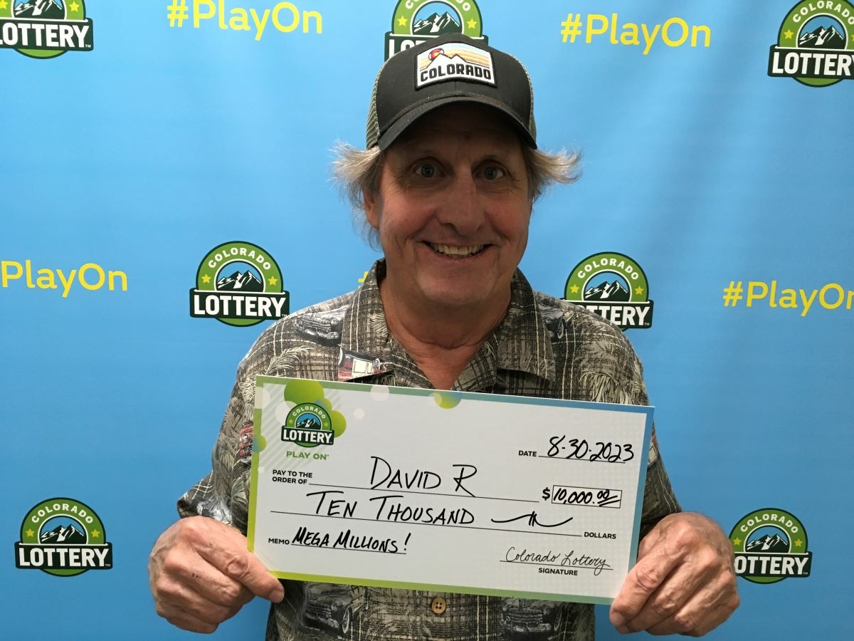 David R. of Littleton holding an oversized check for $10,000 in front of Colorado Lottery background.