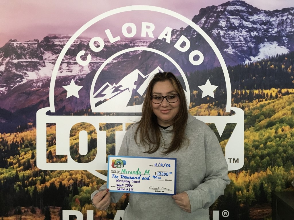 Ganador sosteniendo un cheque gigante frente al fondo de Colorado Lottery
