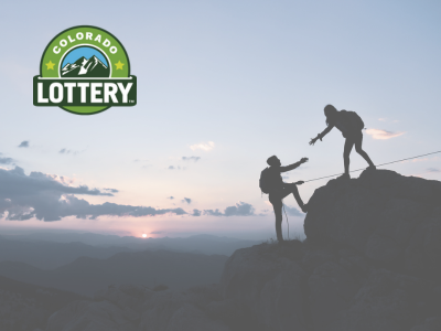 silhouette of two people helping each other on top of a mountain at sunset