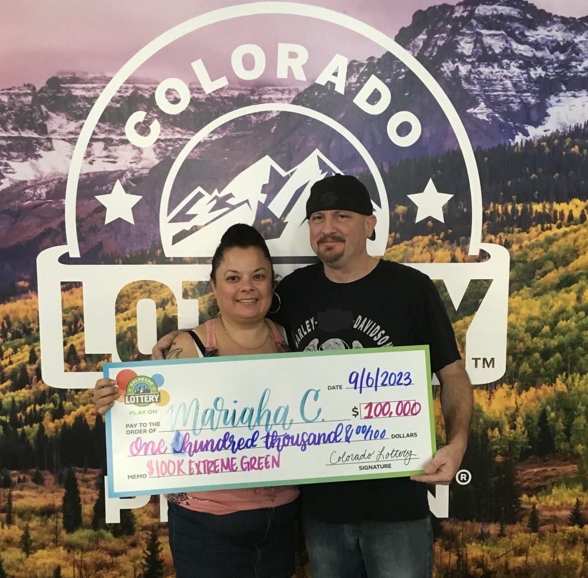 Mariaha C. of Lamar holding an oversized check for $100,000 in front of Colorado Lottery background.