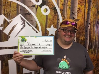 Richard D. holding an oversized check for $5,181 in front of Colorado Lottery background