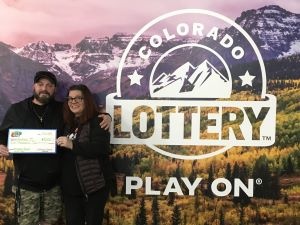 Andrea M. holding an oversized check for $5,000 in front of Colorado Lottery background