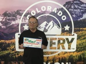 Alan F.  holding an oversized check for $2,500 in front of Colorado Lottery background