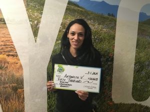 Antoinette V. holding an oversized check for $50,000 in front of Colorado Lottery background