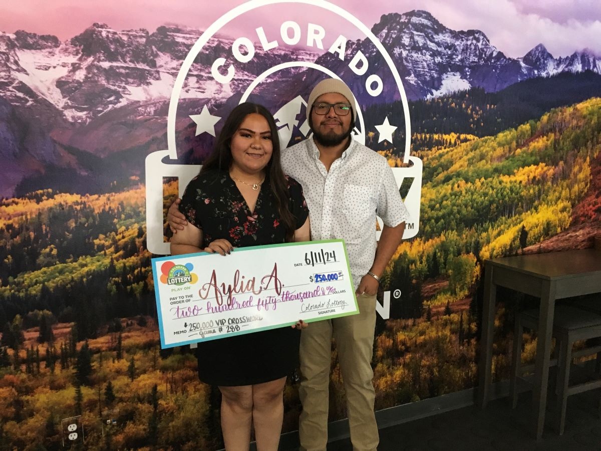 Aylia A. holding an oversized check for $250,000 in front of Colorado Lottery background